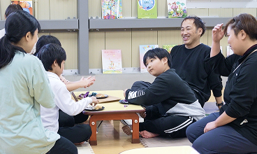 スタッフと子どもたちが和やかに笑顔で話している教室の風景